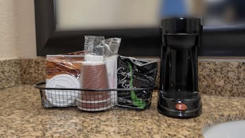 A kitchen counter with a coffee maker, a basket containing various items, and a bag of coffee.