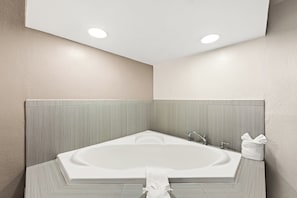 A modern bathroom with a freestanding bathtub, recessed ceiling lights, and a towel rack.