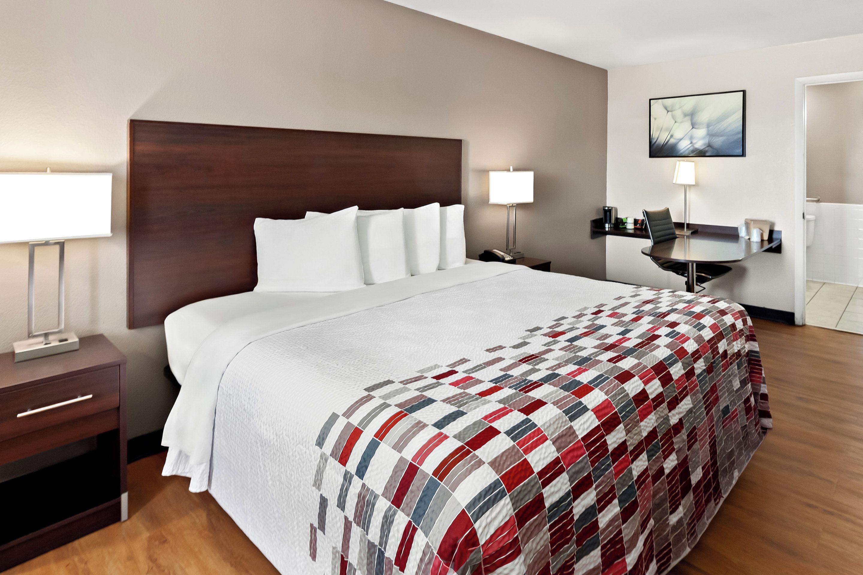A hotel room with a large bed, a desk, and a chair.