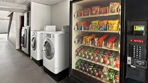 Eine Waschsalon mit Waschmaschinen und Trocknern, sowie ein Verkaufsautomat mit Snacks und Getränken.