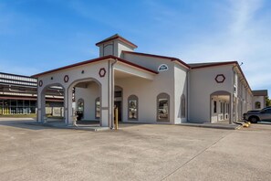 A building with a modern architectural design, featuring arched doorways and a flat roof. - Red Roof Inn Muscle Shoals (Muscle Shoals)