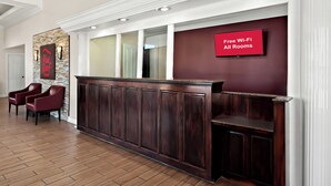 A reception area with a dark wood reception desk, a red sign indicating free Wi-Fi, and two red leather chairs.