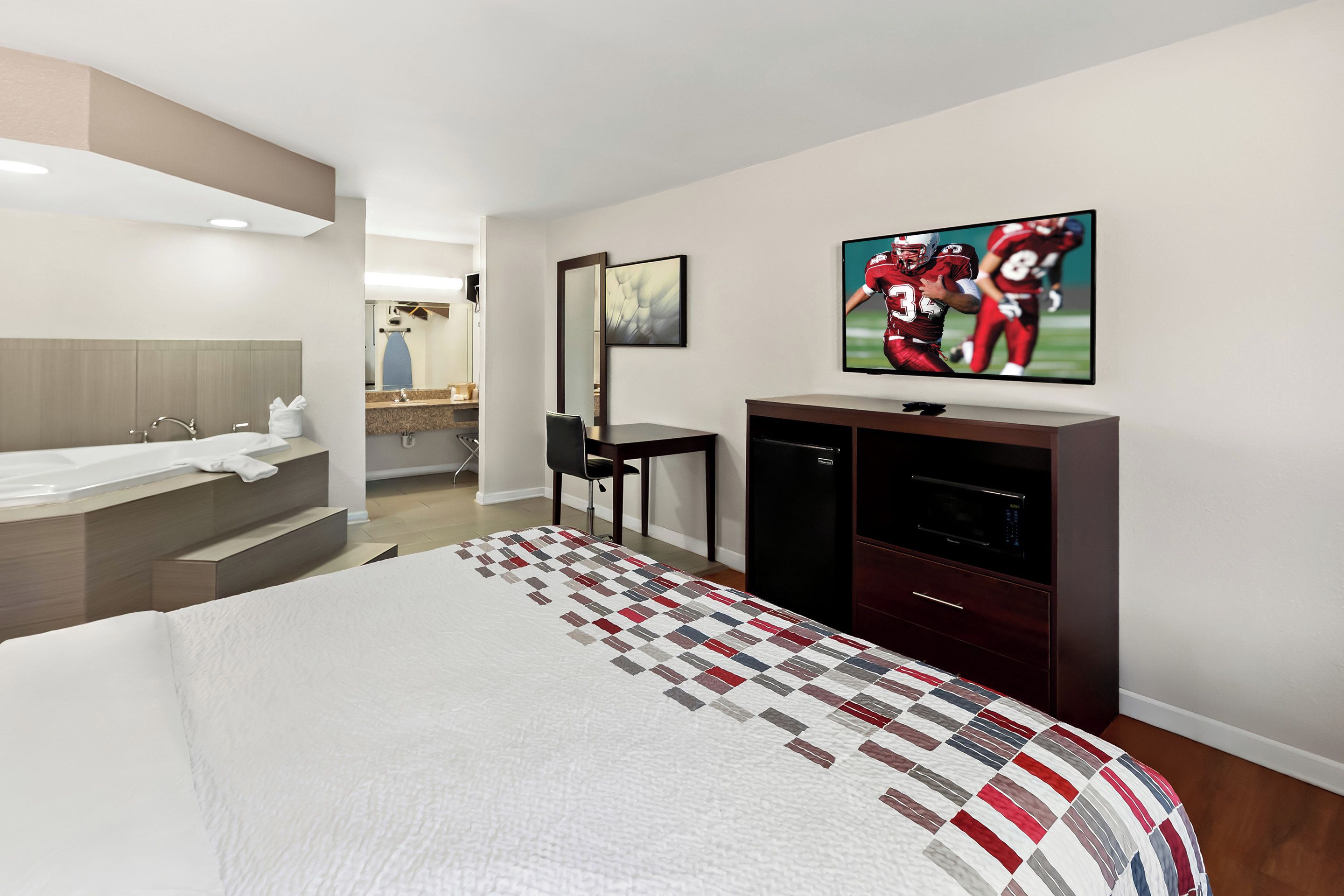 Una habitación de hotel con una cama grande, televisión, escritorio y baño.