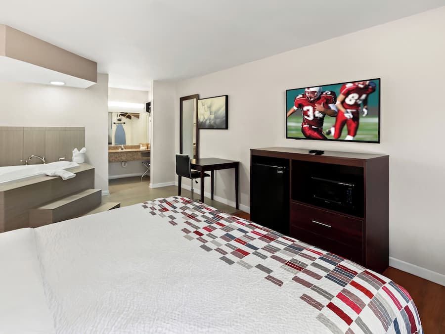 Une chambre d’hôtel avec un grand lit, une télévision, un bureau et une salle de bain.