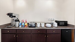 A kitchenette with a coffee maker, toaster, microwave, and various containers.