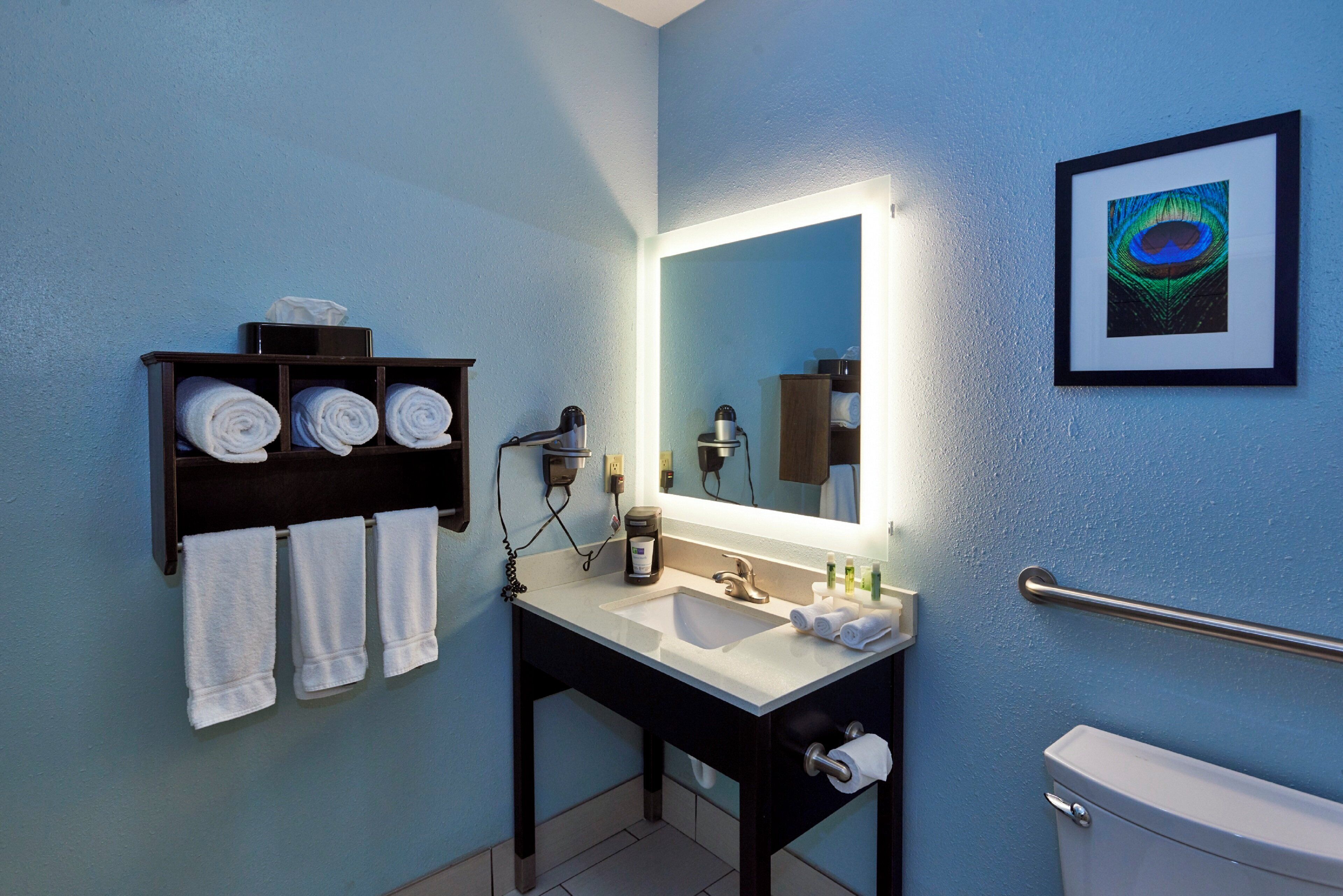 A bathroom with a sink, mirror, towel rack, and toilet.