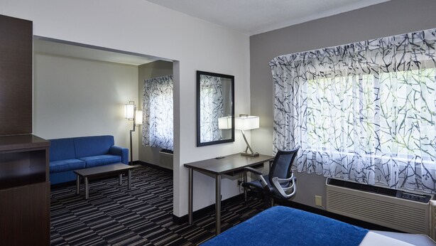 A hotel room with a bed, a desk, a chair, a sofa, and a large window with a view. - Holiday Inn Express & Suites Birmingham South - Pelham by IHG (Pelham)