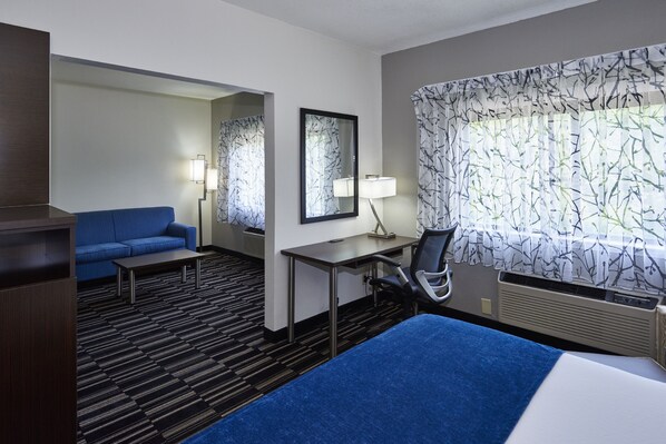 Ein Hotelzimmer mit Bett, Schreibtisch, Sessel, Sofa und einem großen Fenster mit Aussicht.