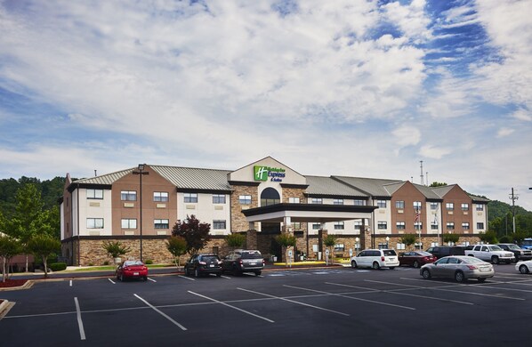 Un hotel Holiday Inn Express con fachada de ladrillo, varios espacios de estacionamiento y un cielo despejado.