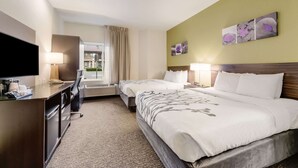 A hotel room with a large bed, a desk with a TV, and a window with curtains.