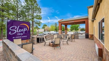 Un patio al aire libre con una parrilla, asientos y un letrero de Sleep Inn by Choice Hotels.