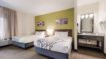 A hotel room with two beds, a bathroom with a vanity, and artwork on the walls.