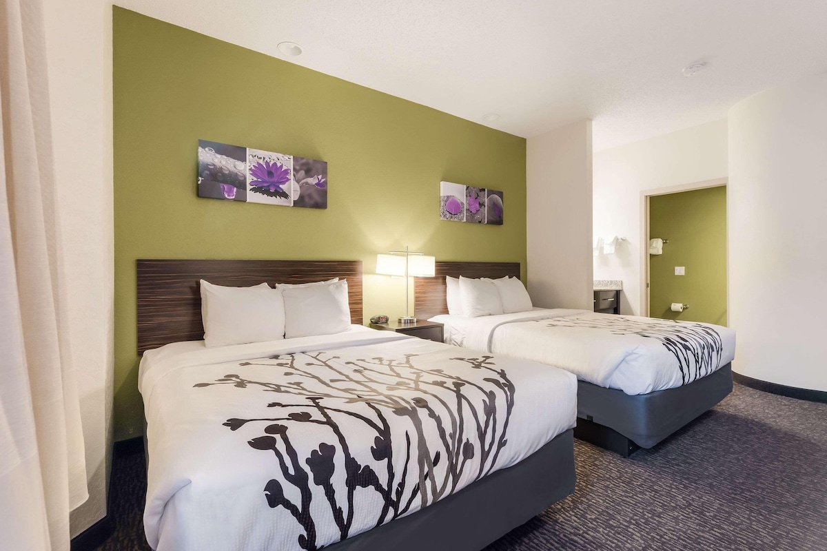 A hotel room with two beds, green walls, and floral artwork.
