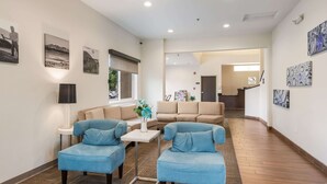 A modern living room with blue sofas, a small table with a vase, and artwork on the walls.