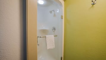 A glass-enclosed shower with a white towel hanging on a metal bar.