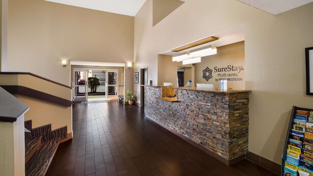 Zona de recepció d'hotel amb un taulell de pedra, una escala i un passadís que condueix a altres habitacions.