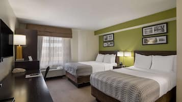 A hotel room with two beds, a desk, a telephone, and a window with curtains.