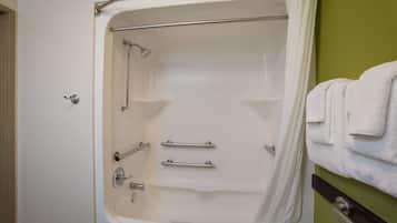 Une baignoire équipée de barres d’appui, d’un pommeau de douche et d’un porte-serviettes.