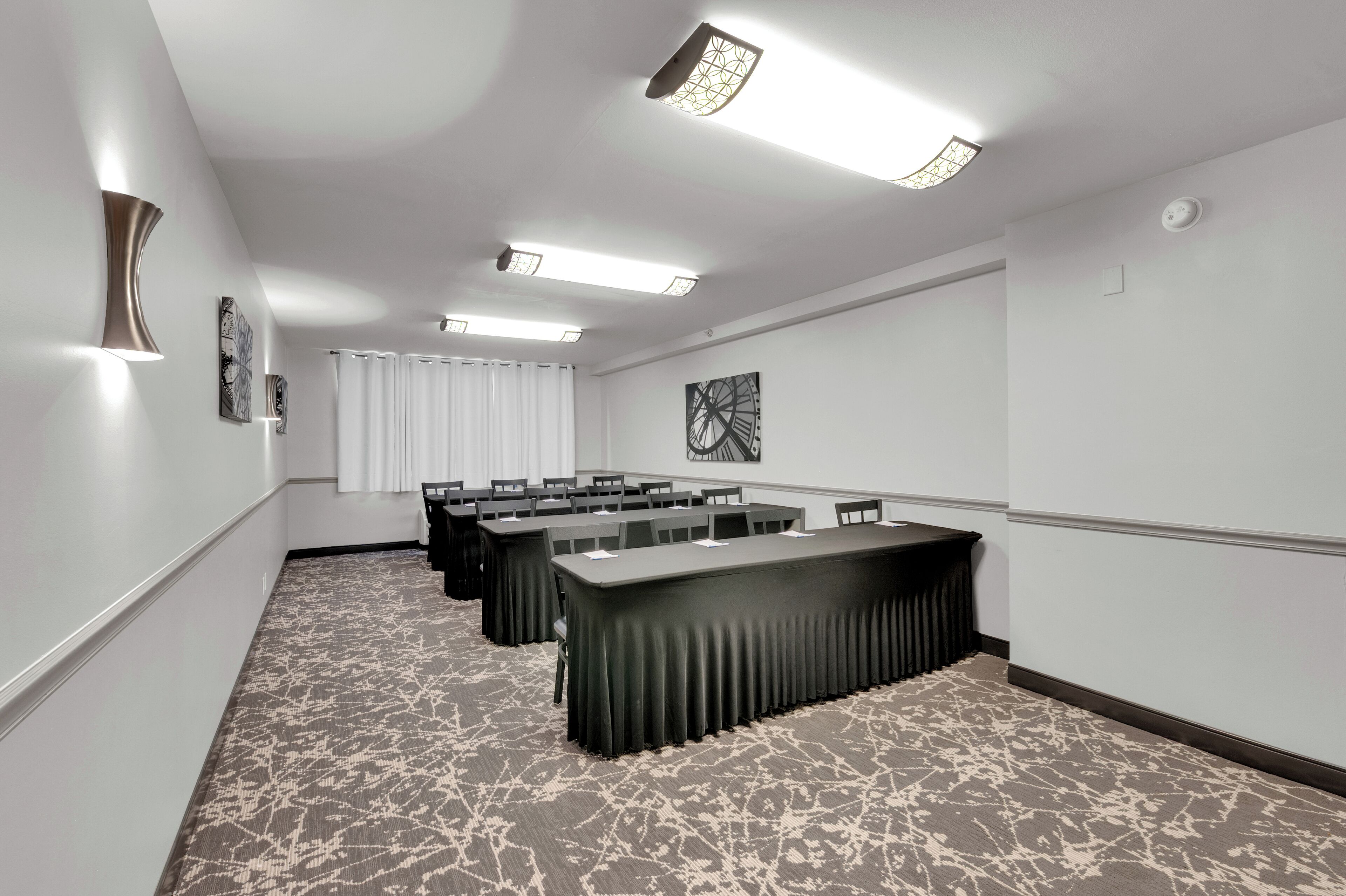 A conference room with a long table, multiple chairs, and a patterned carpet.