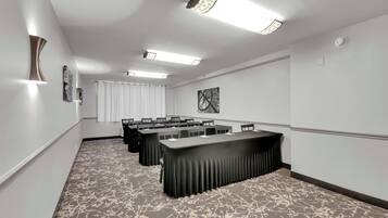 A conference room with a long table, multiple chairs, and a patterned carpet.