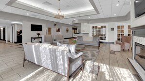 A spacious living room with a modern chandelier, a fireplace, and a large television on the wall.