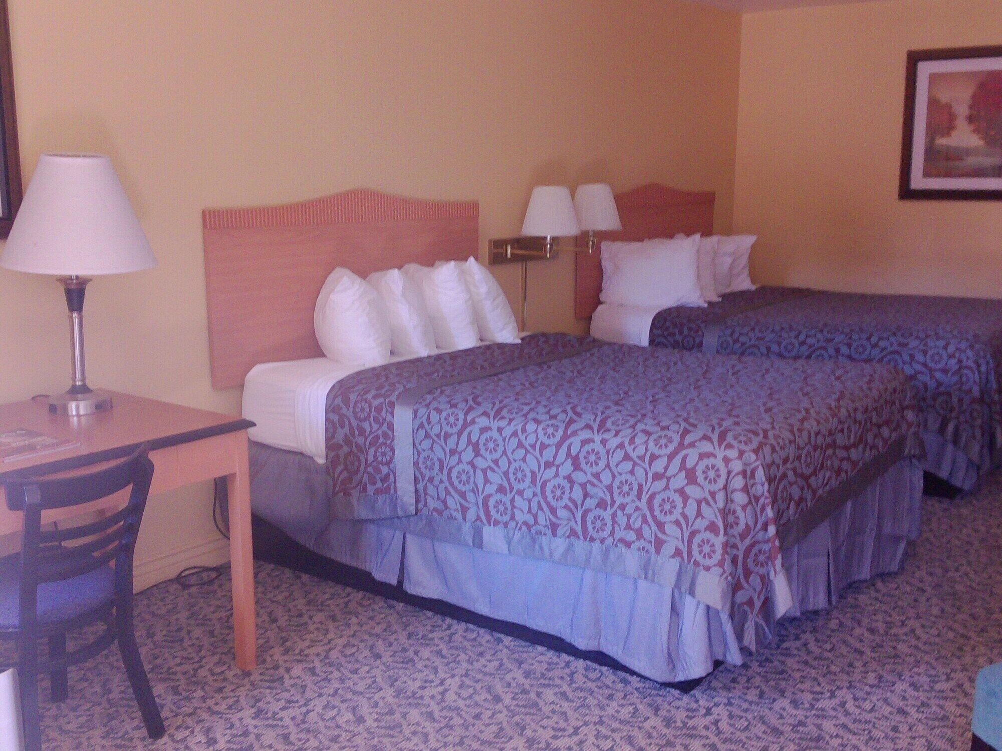 A hotel room with two beds, a desk, and a chair.