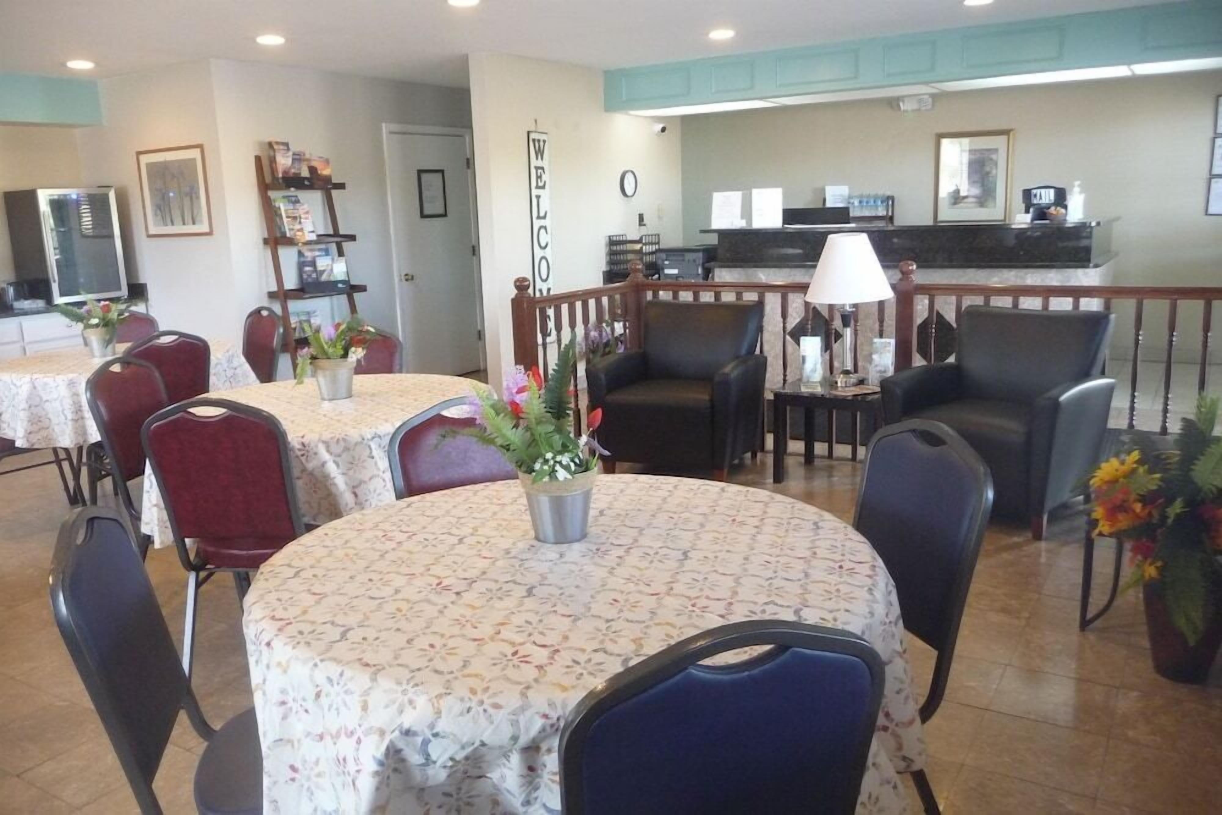 A dining area with round tables, chairs, and a reception desk.