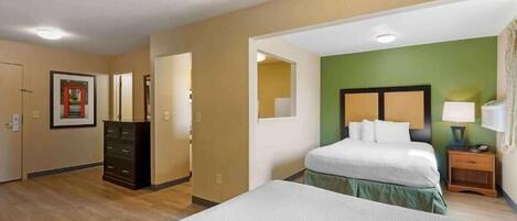 Een hotelkamer met een groot bed, een kaptafel, een nachtkastje en een groene accentmuur.