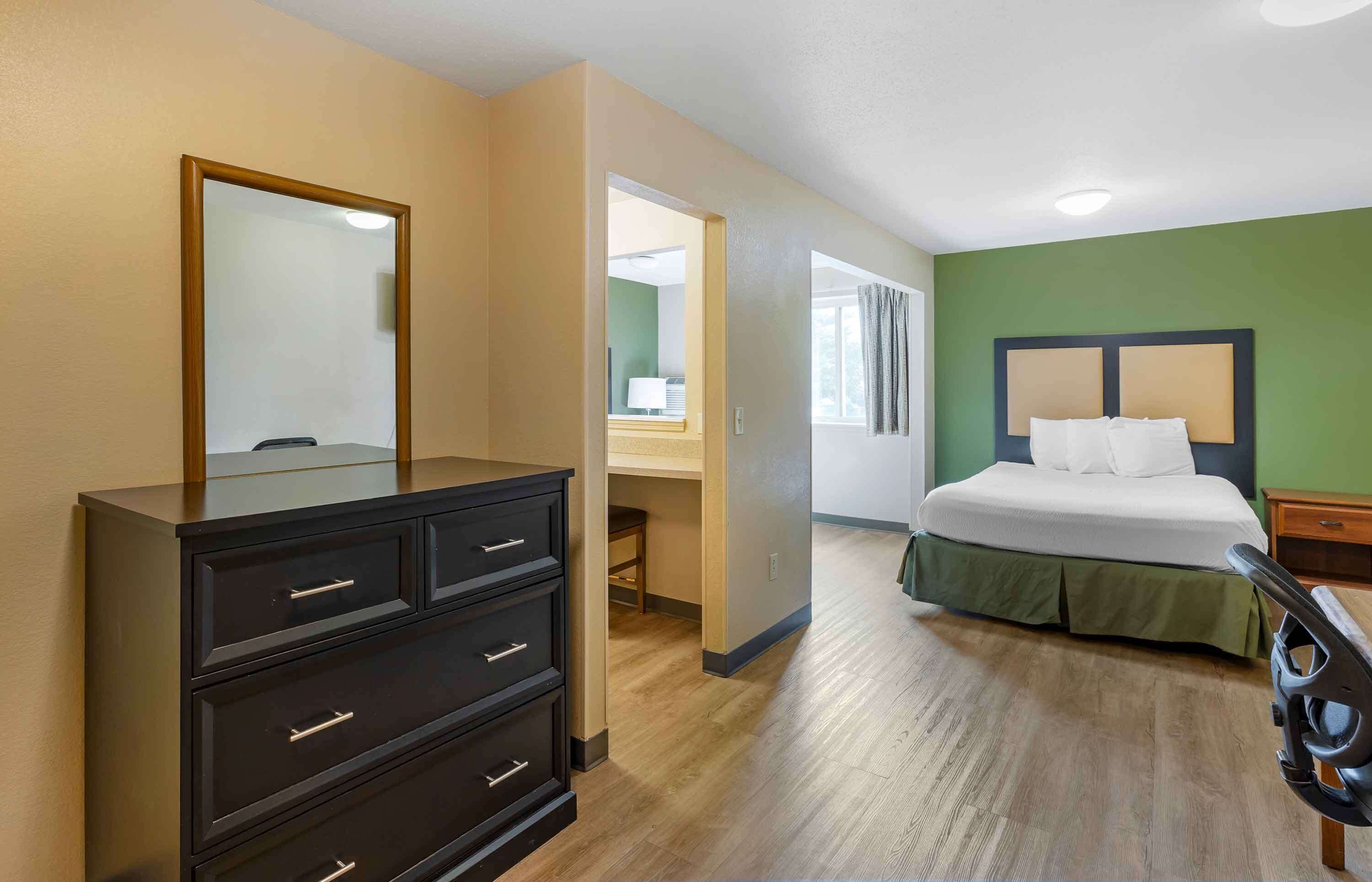 Una habitación de hotel con una cama, un tocador, un escritorio y un espejo.