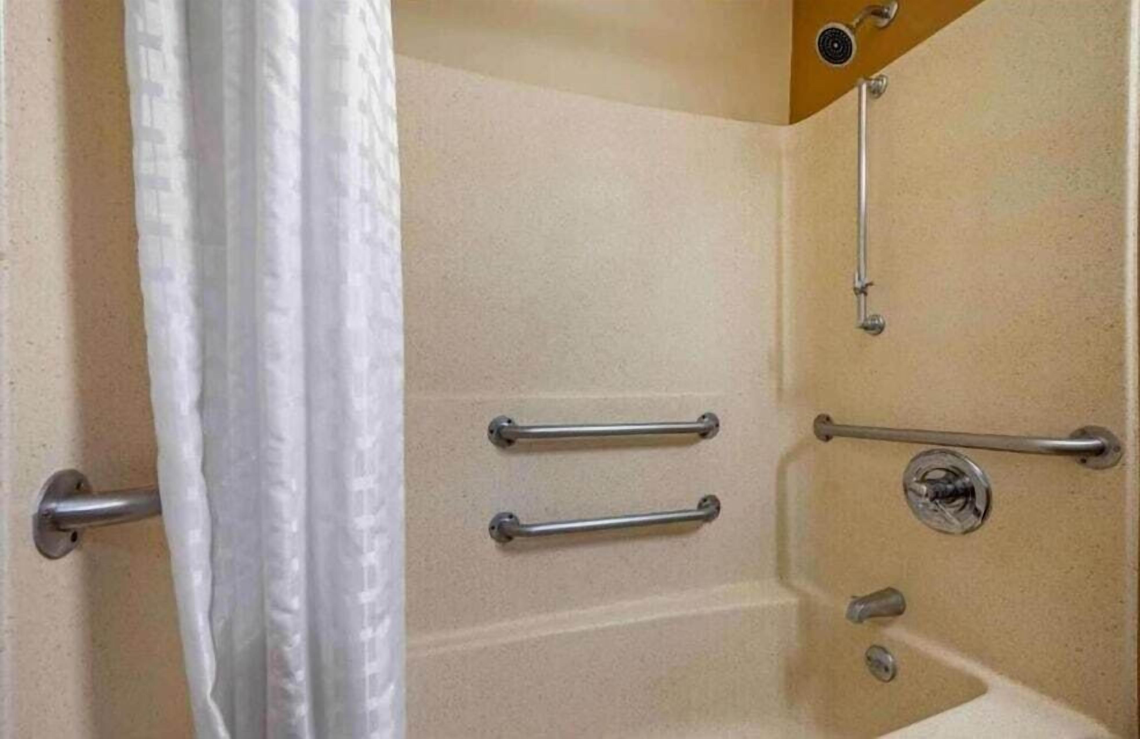 A shower with grab bars and a handheld showerhead.