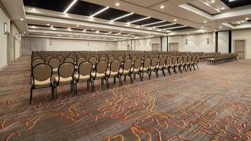 A large conference room with rows of chairs, carpeted floor, and modern lighting fixtures.