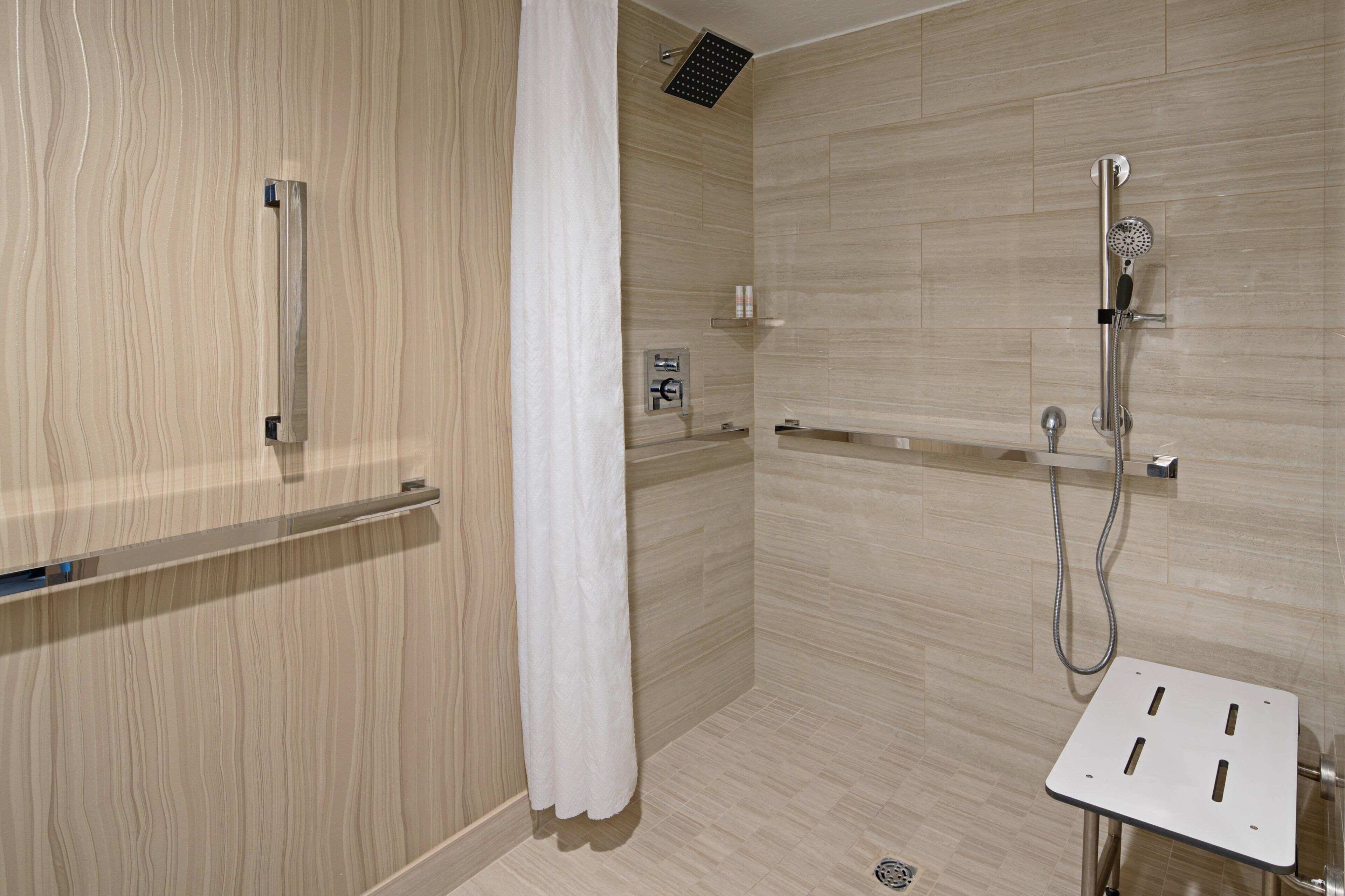 A modern shower area with a wooden wall, a white shower curtain, and a handheld showerhead.
