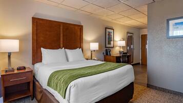 A hotel room with a large bed, two bedside tables, a nightstand, a desk, and a chair.