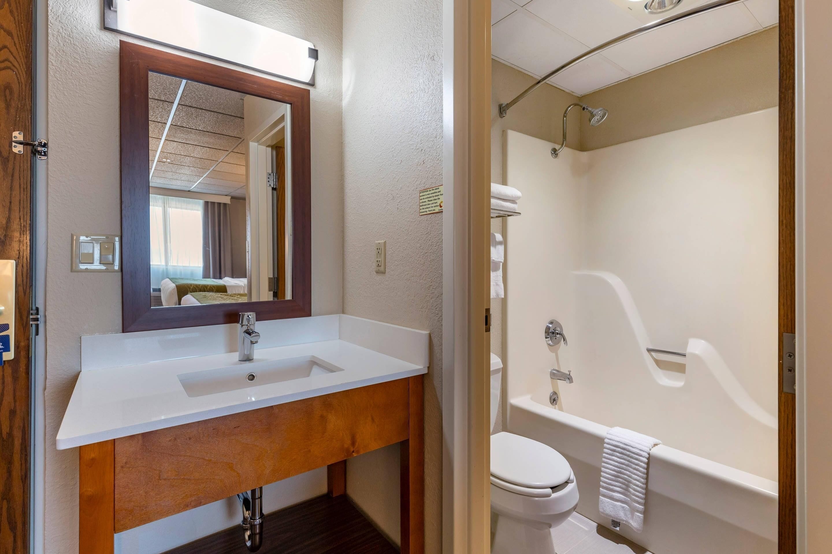 A bathroom with a white sink, mirror, and bathtub.