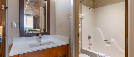 Un baño con lavamanos blanco, espejo y bañera.