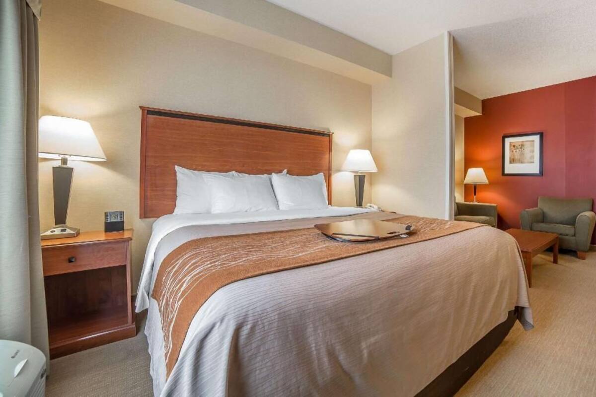 A hotel room with a large bed, two bedside tables with lamps, a small table, and a chair.
