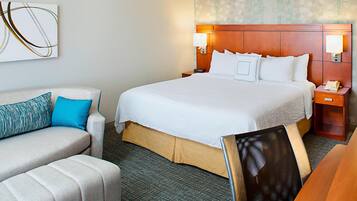 A hotel room with a large bed, a sofa, a chair, and a desk.