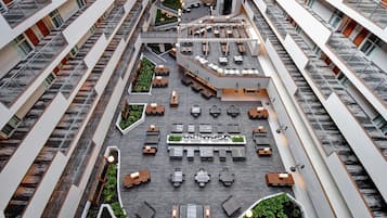 A multi-level atrium with outdoor seating areas, staircases, and a central garden.