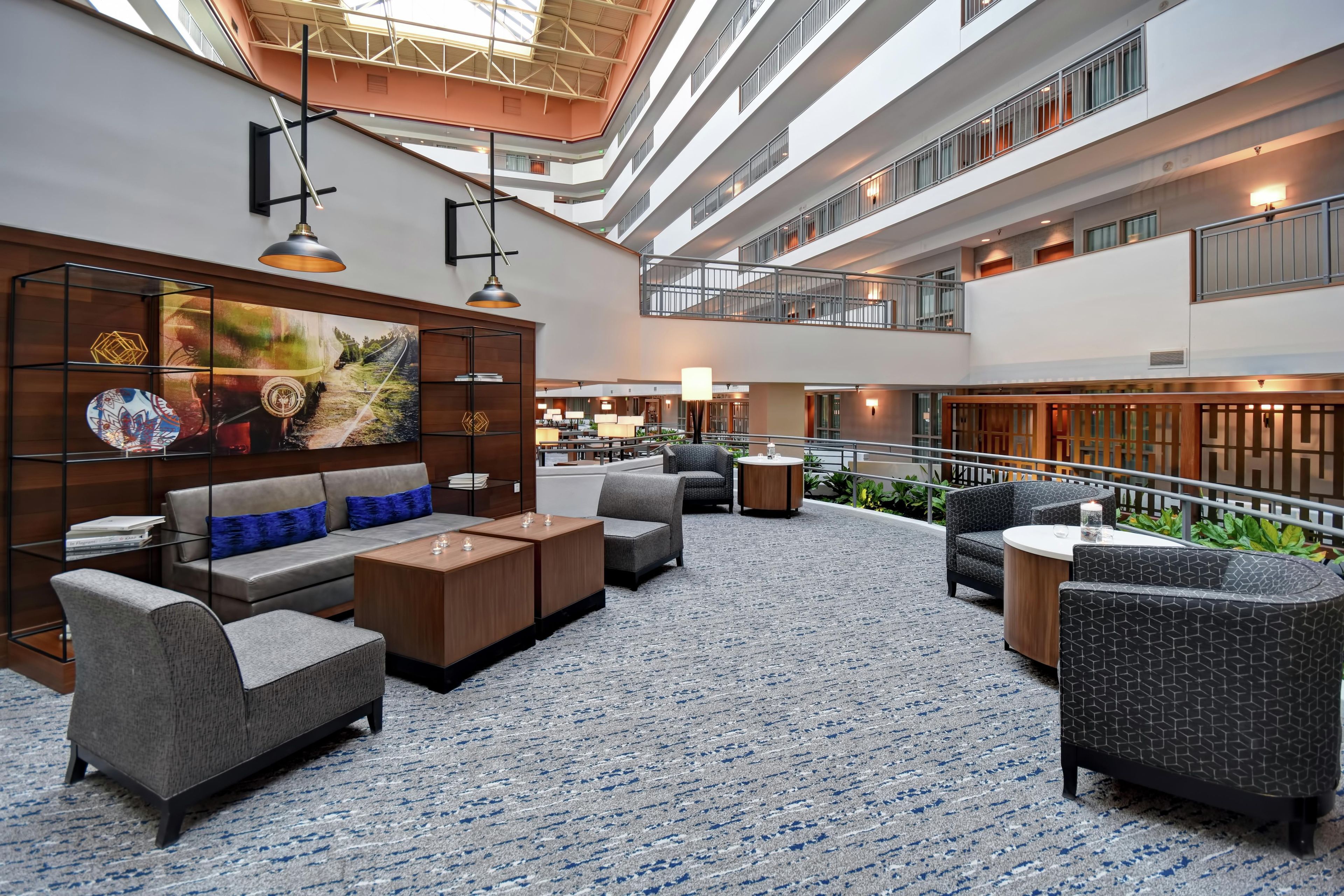 A spacious lobby with a high ceiling, modern furniture, and a large painting on the wall.