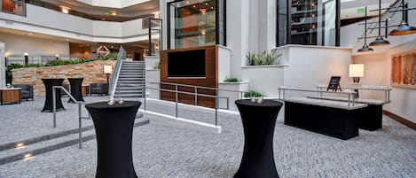 A spacious indoor area with multiple levels, a central staircase, and a seating area with tables and chairs.