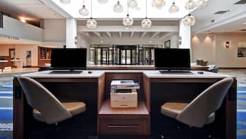 A hotel reception desk with two computer stations, a printer, and a revolving door entrance.