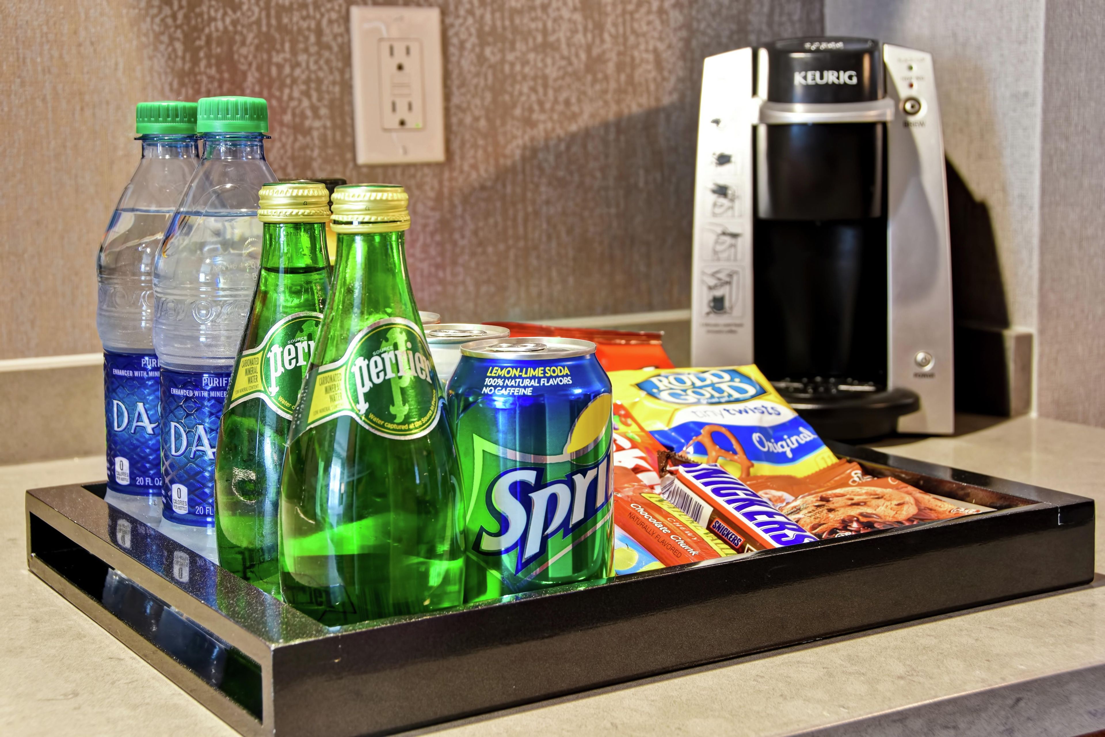 Un plateau contenant des bouteilles d’eau, des sodas et des en-cas, posé sur un comptoir.