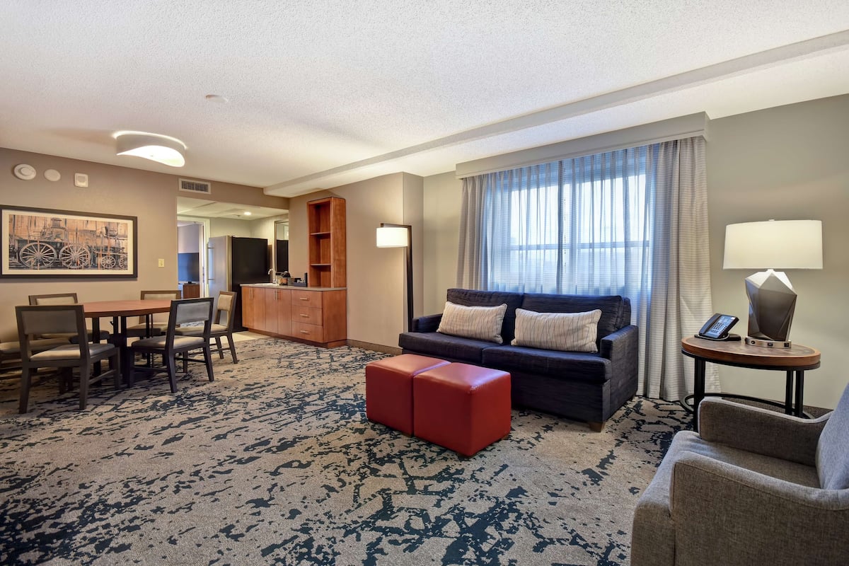 A hotel room with a dining area, a sofa, a coffee table, and a TV.