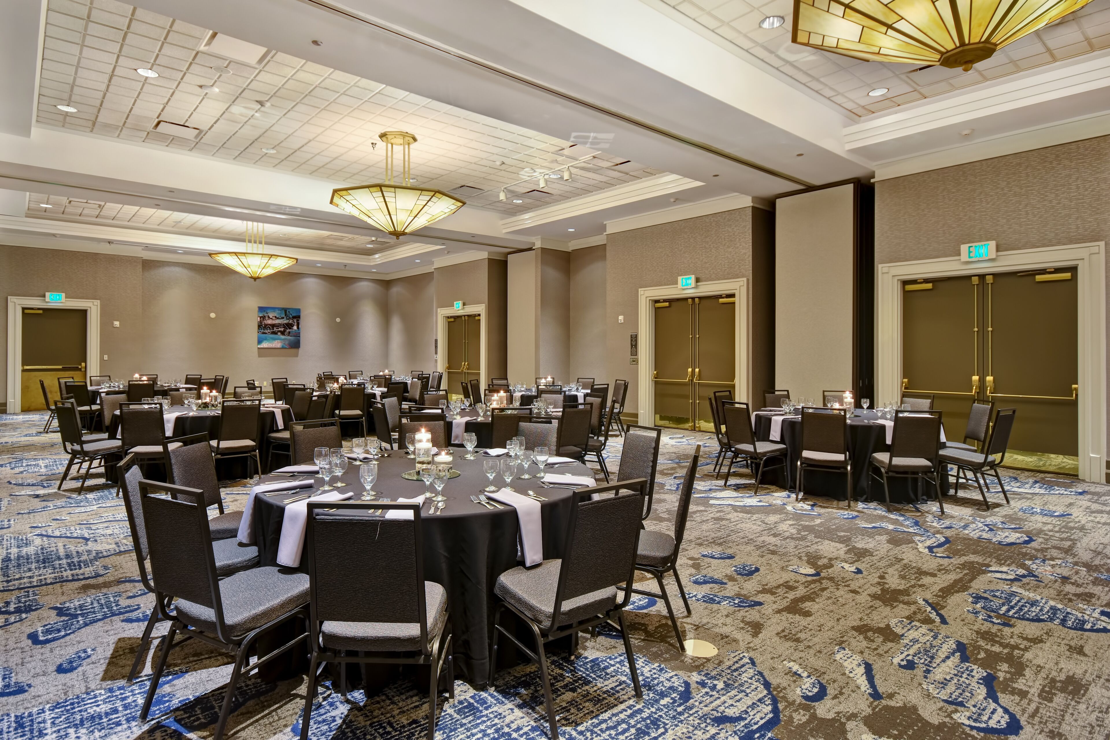 A conference room with round tables, chairs, and a patterned carpet.