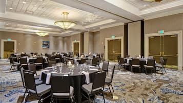 A conference room with round tables, chairs, and a patterned carpet.