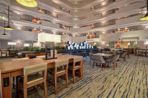 A multi-level hotel lobby with dining areas, seating arrangements, and a central decorative feature. - Embassy Suites by Hilton Omaha Downtown Old Market (Omaha)