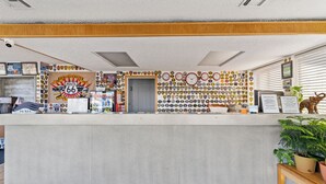 A reception desk with a Route 66 themed wall, a clock, and a small plant. - Economy Inn Barstow (Barstow)