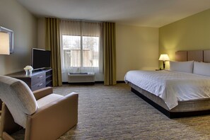 A hotel room with a bed, a desk with a TV, a chair, and a window with curtains. - Candlewood Suites Wichita East by IHG (Wichita)