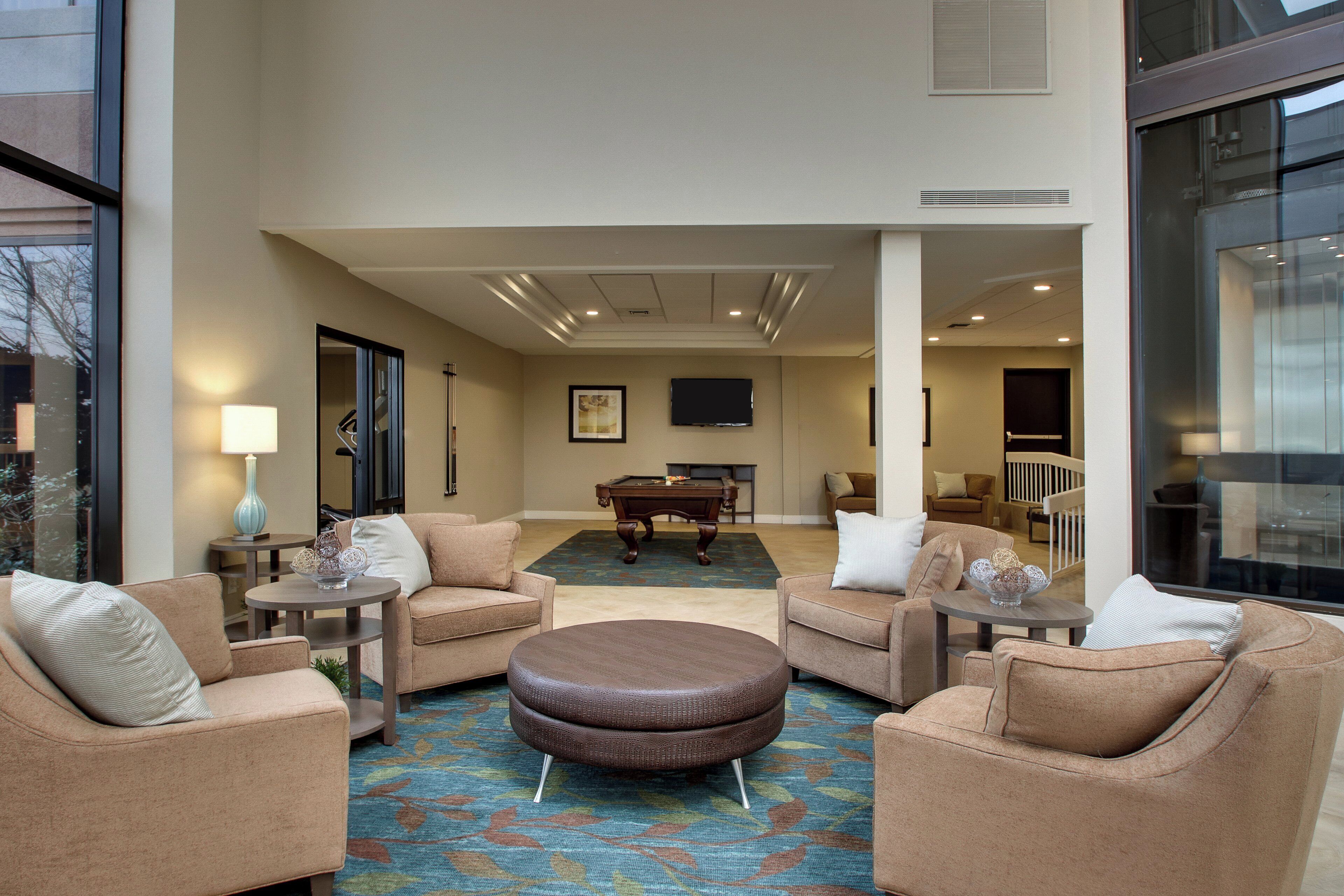 A spacious lobby with a pool table, comfortable seating, and a large window.