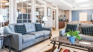 A living room with a grey sofa, a coffee table, and a dining area with chairs.